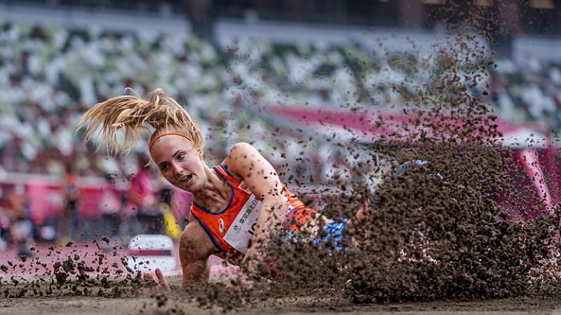 A woman falling in a sand pit in a long jump competition