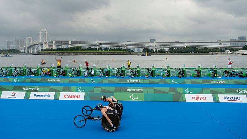 Two wheelchair racers neck-in-neck down home stretch