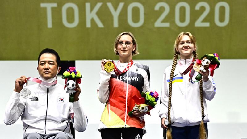 A man in a wheelchair standing next to two women on a podium