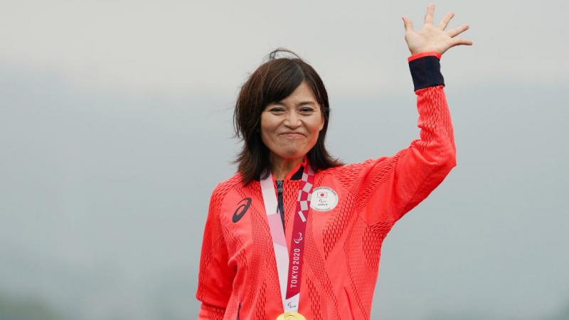 Japanese woman waves with gold medal around her neck