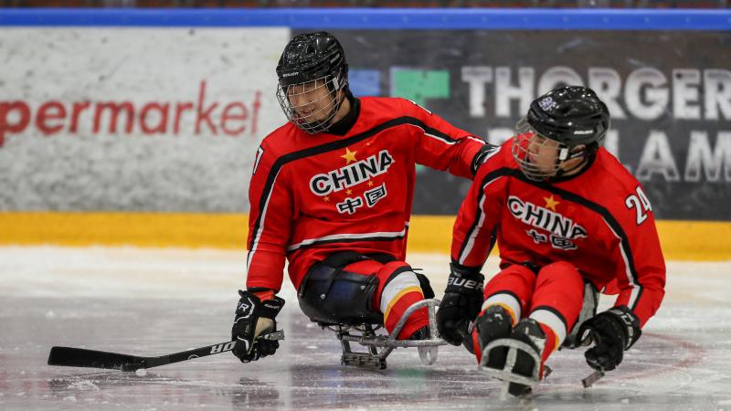 Chinese Para ice hockey player skating on a sled while controlling the puck with his right stick