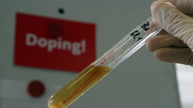 A test tube with a urine sample with a sign that says; "Doping!," behind it