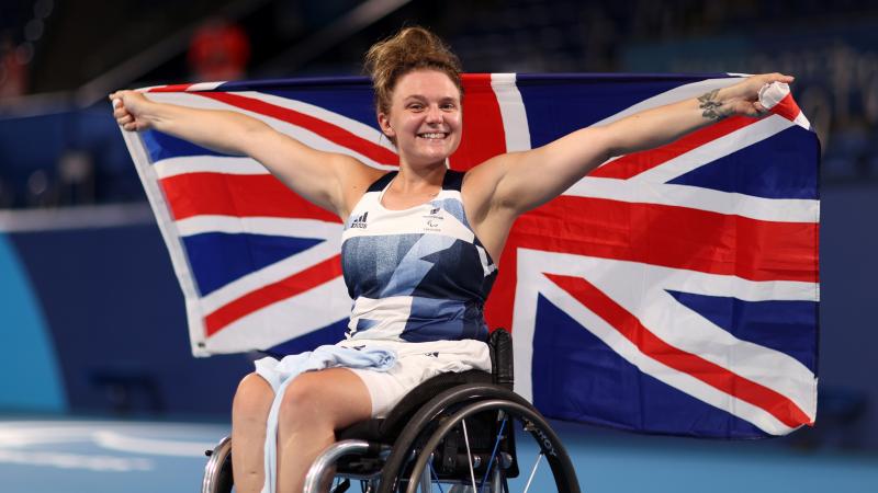 Jordanne Whiley smiles to the camera while holding the British flag