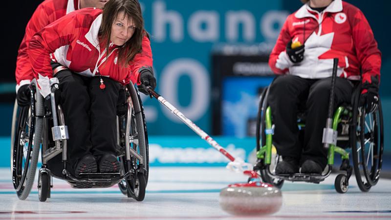 Canadian wheelchair curler Ina Forrest pushes the stone on the ice rink