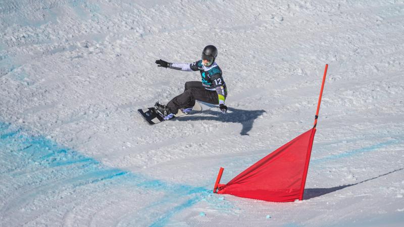 A man on a snowboard with his arms stretched going into the curve.