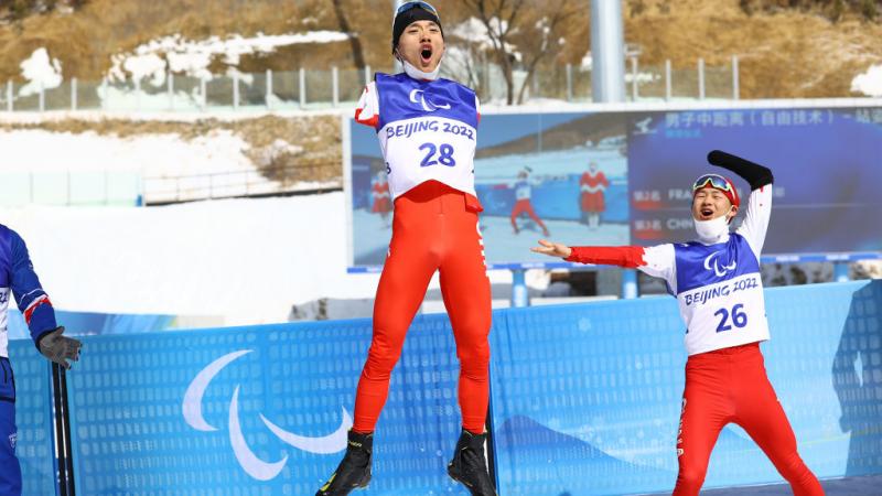 Chenyang Wang of China reacts after winning the gold  as compatriot Jiayun Cai looks on following the Men's Middle Distance Free Technique Standing at the Beijing 2022 Paralympic Winter Games at Zhangjiakou National Biathlon Centre. 