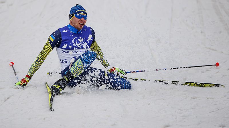 Oleksandr Kazik falls to the ground in a flurry of snow after winning gold at Beijing 2022