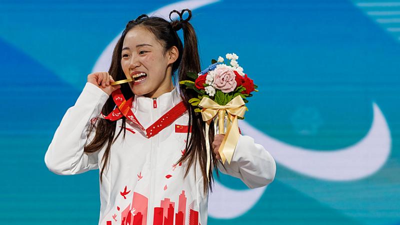 Menqiu Zhang bites her gold medal