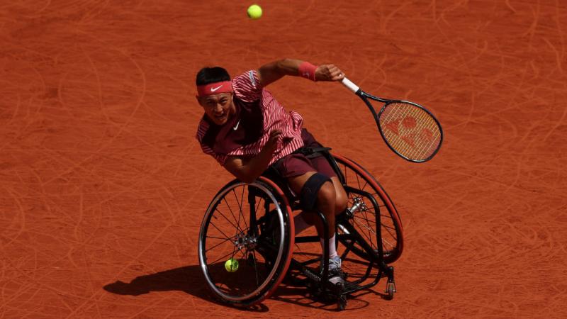 A male wheelchair tennis player swings his racquet during competition. 
