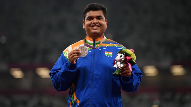 Yogesh Kathuniya smiling and holding up a Paralympic silver medal