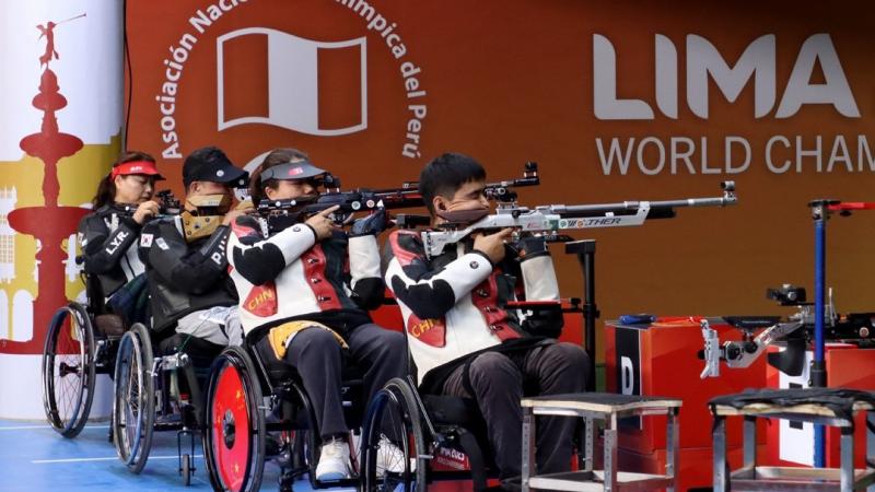 Four rifle shooters in wheelchairs in a shooting range