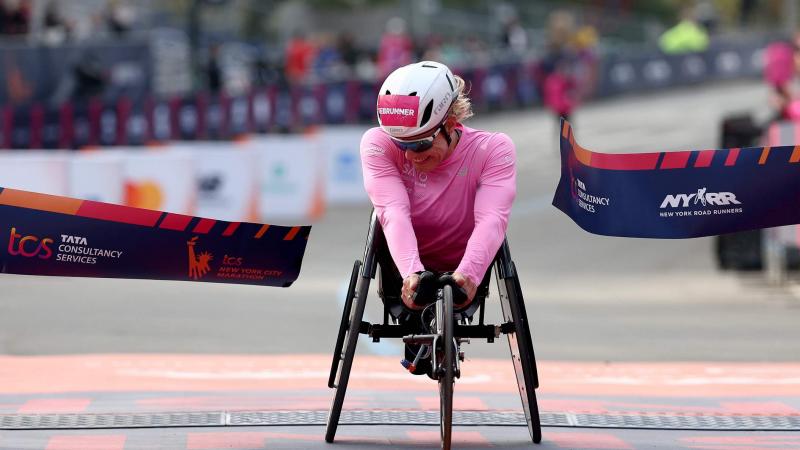 A female wheelchair racer crossing the finish line in a street marathon