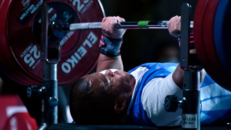 A male Para powerlifter lifts weight during a competition