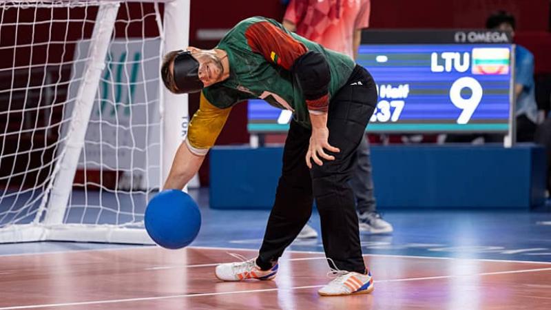 Goalball player Genrik Pavliukianec stands and throws the ball 