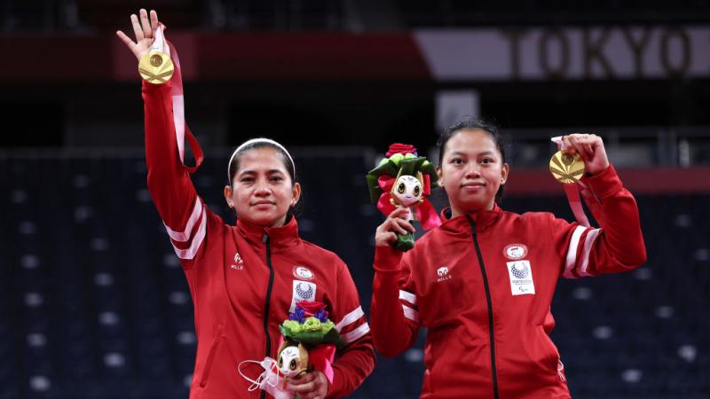 Leani Ratri Oktila and badminton partners raise their medals on the podium
