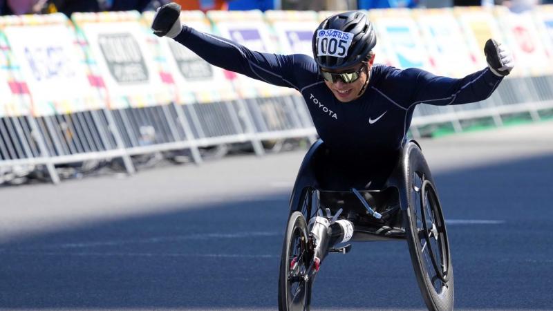 A male wheelchair racer opening his arms in a street marathon