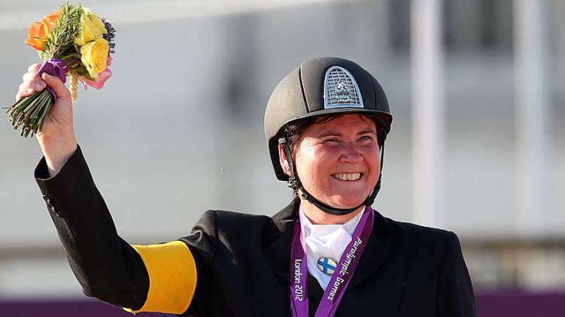 Para rider Katja Karjalainen holding up her silver medal and smiling