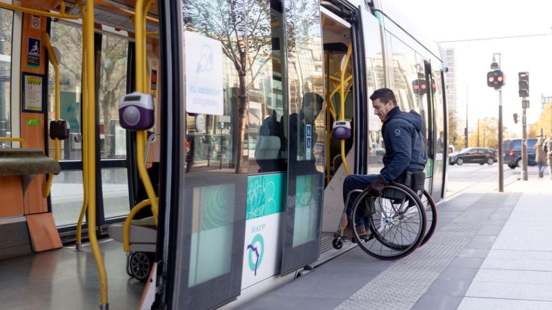 A man in a wheelchair getting on an overground tram. There are no steps between the tram and the platform