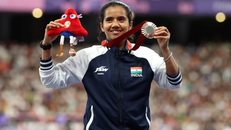 A female athlete with the uniform of India showing a silver medal at Paris 2025
