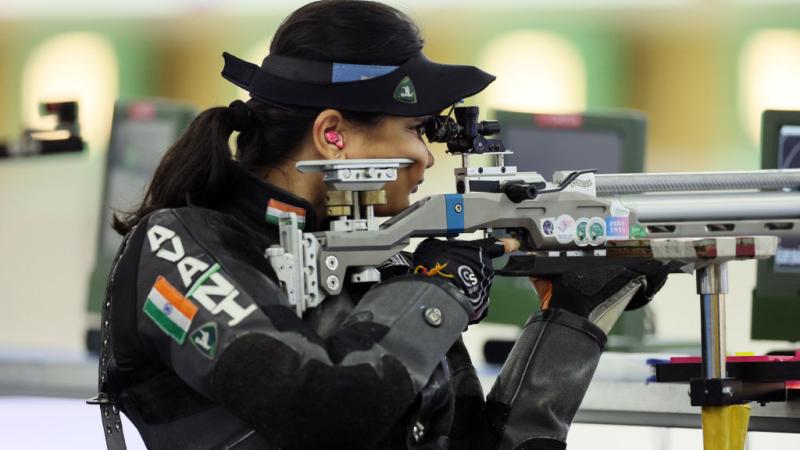 A female rifle shooter competing in a shooting range