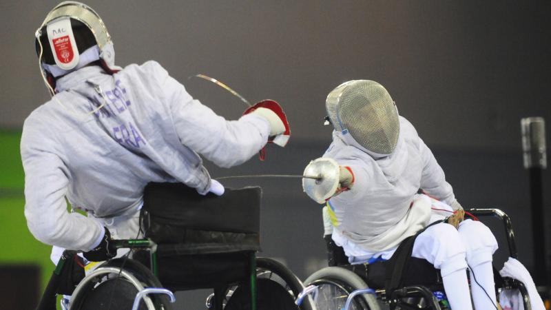 A picture of 2 mens in wheelchair practising fencing
