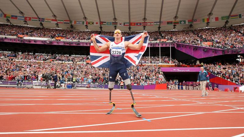 A picture of a man celebrating his victory wearing a flag of Great Britain