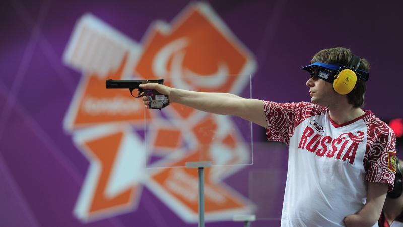 Sergey Malyshev of Russia, wearing glasses, a visor and ear protection shoots his Mixed P3-25m Pistol at an indoor range at The Royal Artillery Barracks