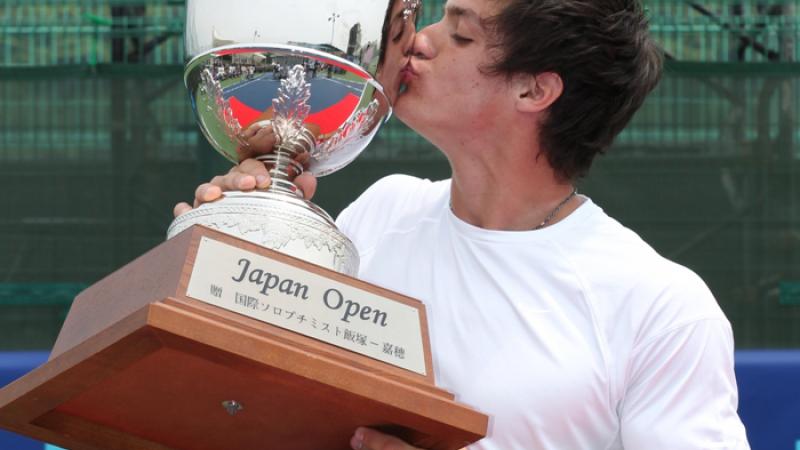 A picture of a man kissing his trophy after his victory
