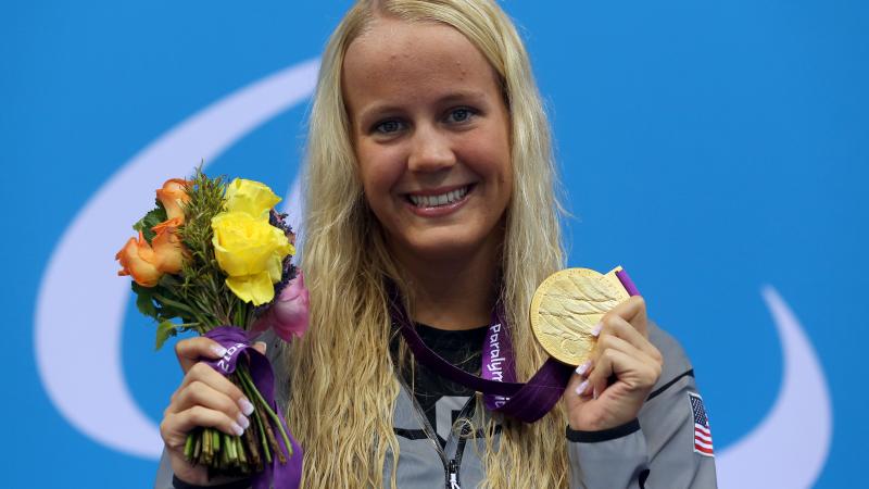 A picture foa a blonde woman showing her gold medal hanging around her neck