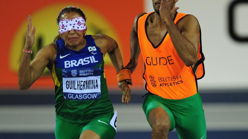 A picture of a blind woman running with her guide during an athletics race.