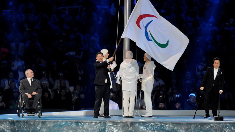 A man waves the Paralympic flag on stage