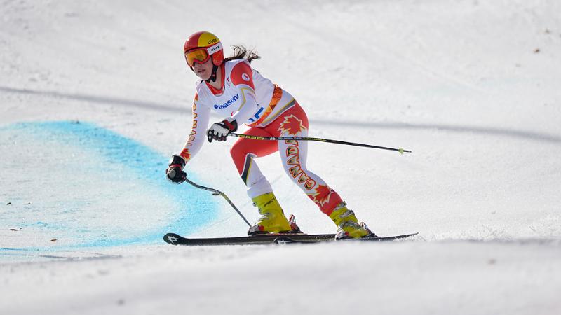 Skier in orange and white ski suit, skis at speed down slope