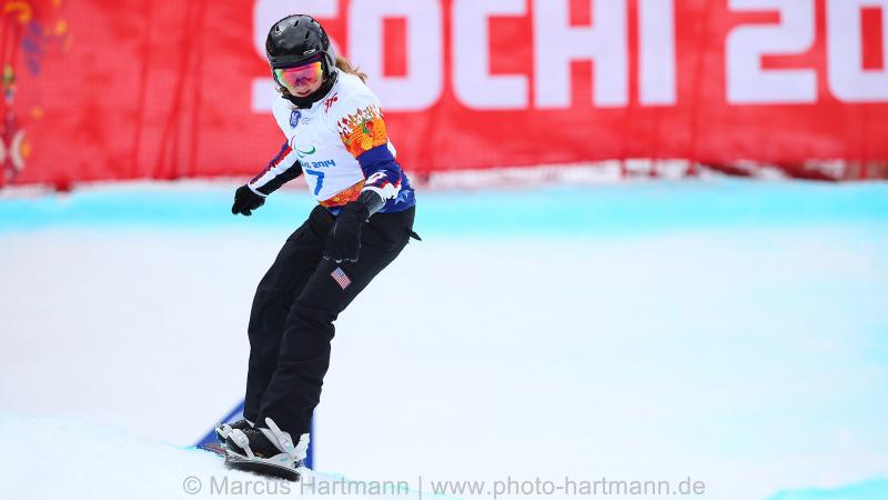 Snowboarder Nicole Roundy rides down course with Sochi 2014 banner in background