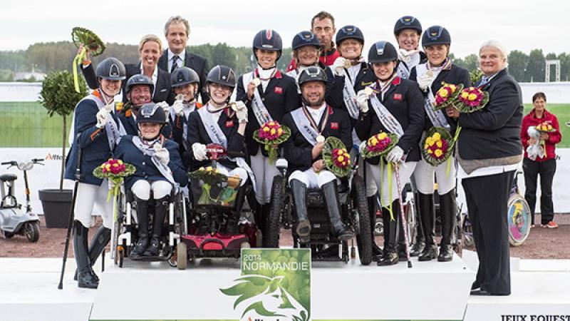 A number of jockeys standing on a podium holding flowers