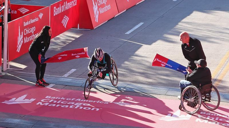 Women in racing wheelchair crossing a finish line