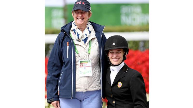 Two women posing for a photo, one with riding clothes