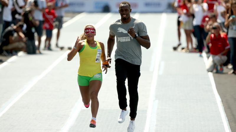 Brazilian Paralympian Terezinha Guilhermina runs with Usain Bolt of Jamaica as her guide during an exhibition in preparation for the Mano a Mano Athletics Challenge at the Jockey Club Brasileiro in Rio de Janeiro, Brazil.