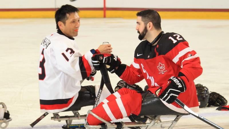 Canada's Greg Westlake, right, shakes hands with Japan's Mamoru Yoshikawa after their preliminary round game at Buffalo 2015.