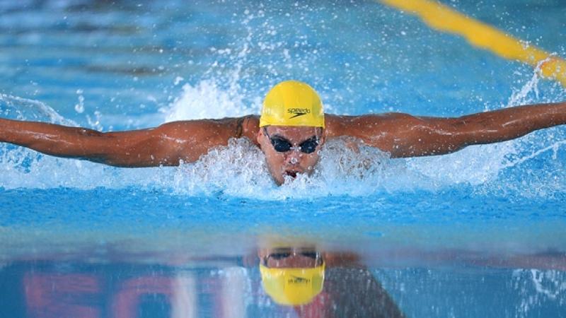 Man with yellow sim cap swimming butterfly