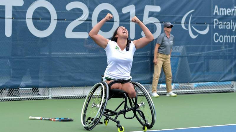 Natalia Mayara celebrating her victory with her hands in the air. She is looking at the sky, her mouth is open