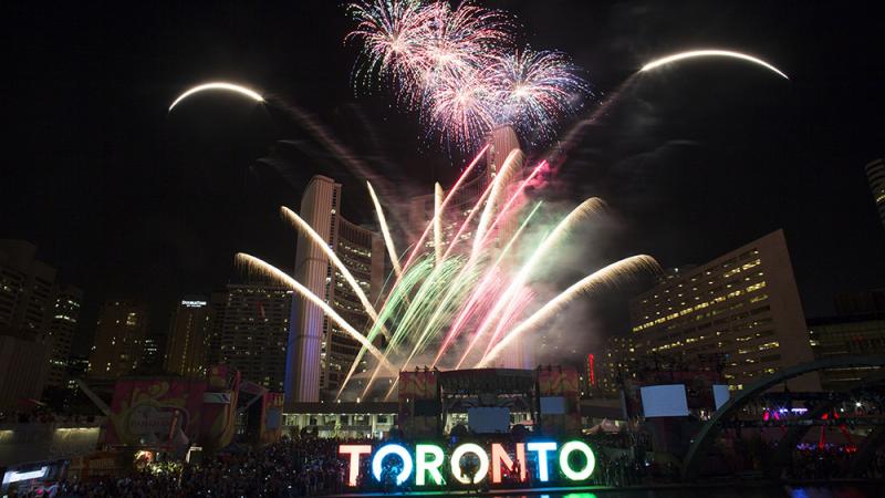 Fireworks in different colors illuminate the night above the 3D Toronto sign
