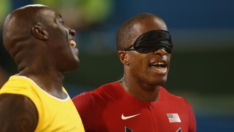 Two men, one blindfolded, laughing