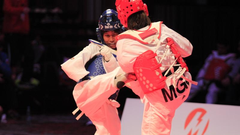 A taekwondo athlete kicks her female opponent 
