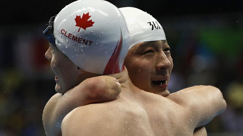 Xu Qing (R) of China is embraced by Nathan Clement (L) of Canada after winning the gold medal in the Men's 50m Butterfly - S6