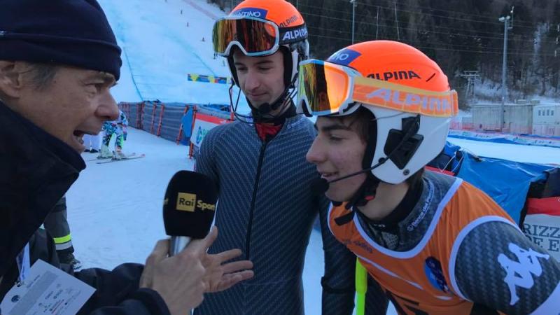 A visually impaired skier and his guide are interviewed