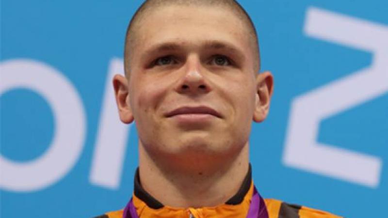 A picture of a man with a gold medal around his neck during a medal ceremony