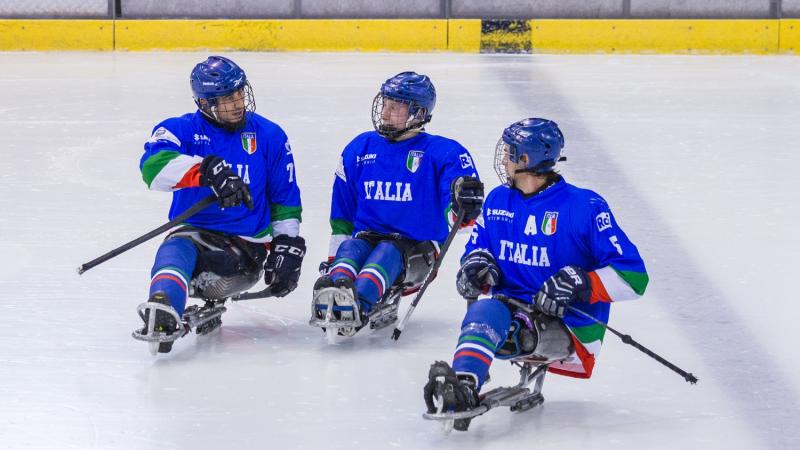 Three Para ice hockey players on ice talking to each other