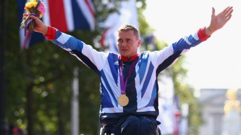 A picture of a man in wheelchair celebrating his victory with a gold medal around his neck