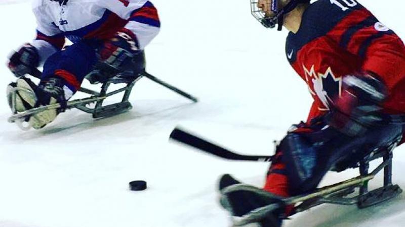 Two Para ice hockey players duel on the ice
