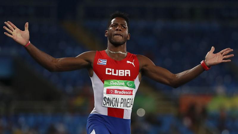 male sprinter crosses finish line with arms outstretched